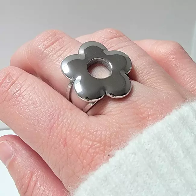 Bague fleur argentée portée sur la main, style moderne et lumineux