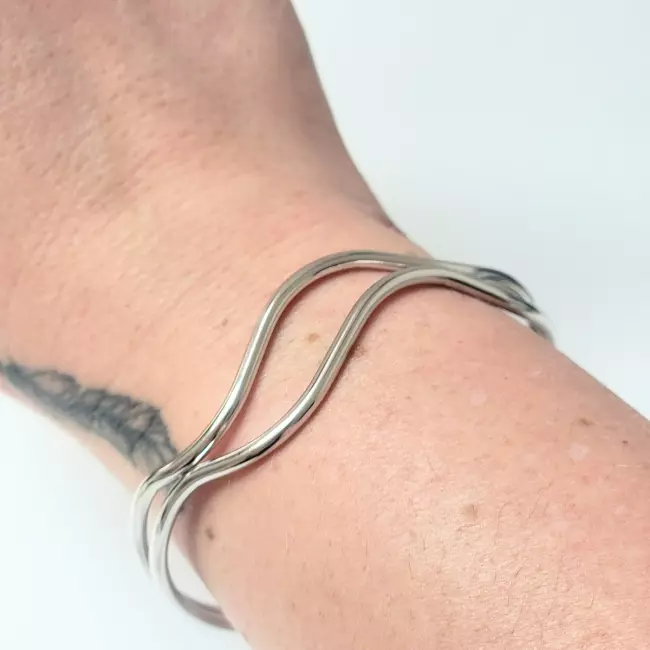 Bracelet jonc vague argenté porté au poignet